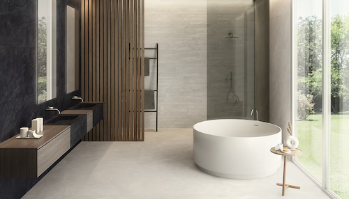 Ergon Cornerstone – płytki gresowe imitujące kamień w nowoczesnej łazience z wanną i ciemną ścianą z efektem łupka